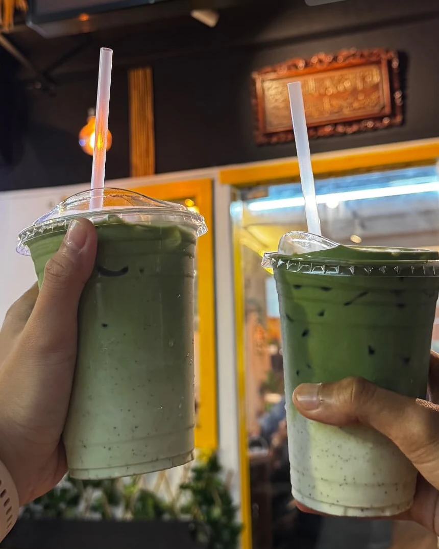 Two iced matchas held up outside the Steambro sign